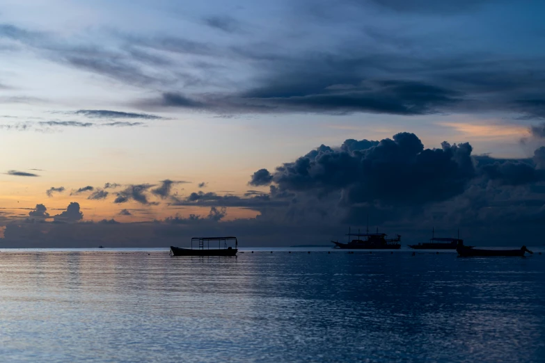 several boats are on the ocean under clouds