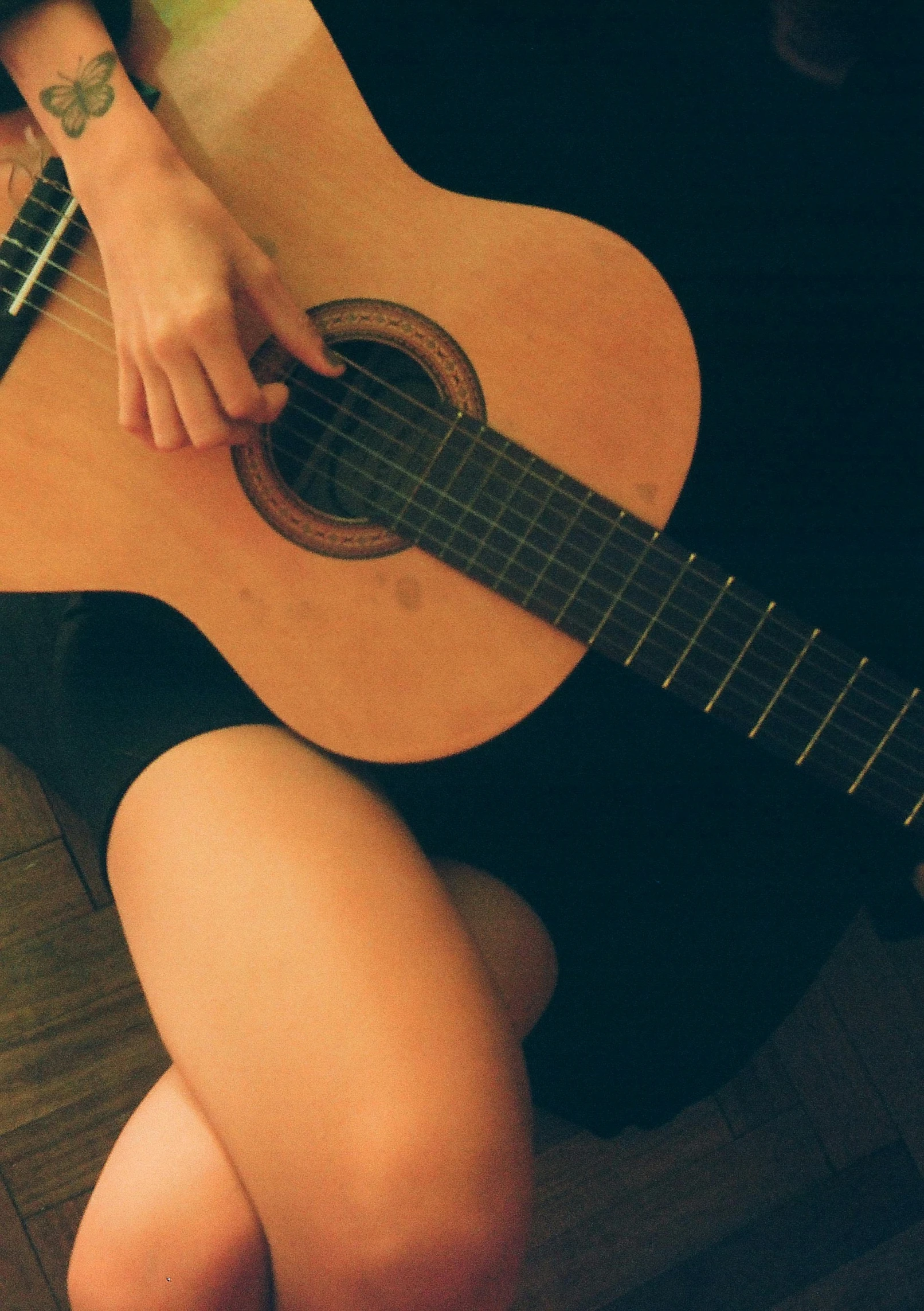 a person with their legs crossed playing the guitar