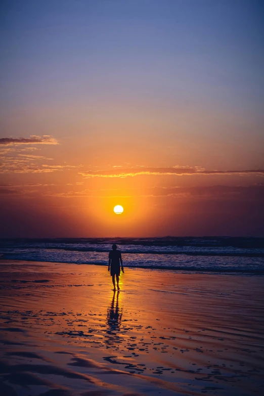 a person standing on a beach at sunset