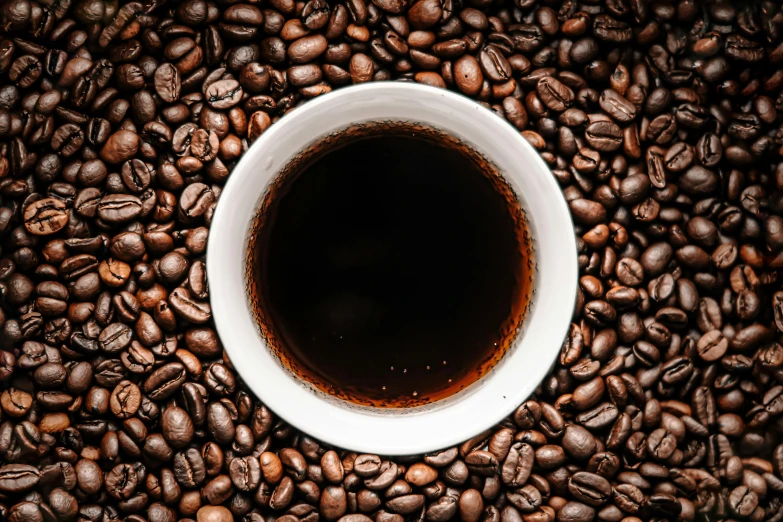 the cup is sitting on a coffee beans