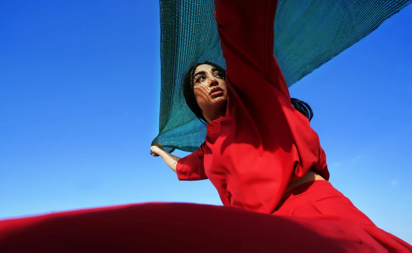 woman in red dress with blue umbrella against clear sky