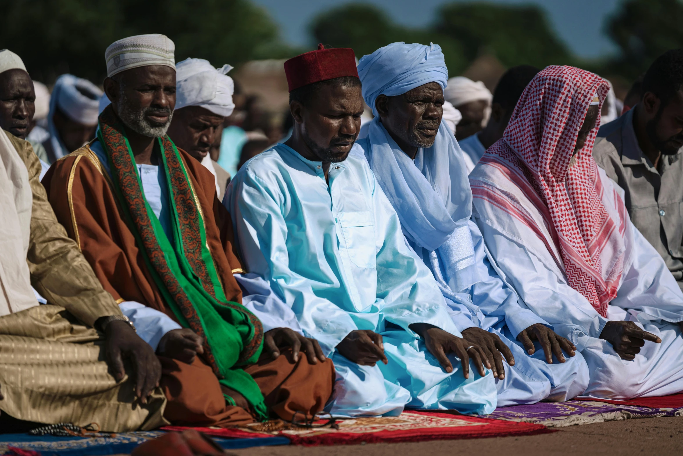 group of men sitting next to each other on a blanket