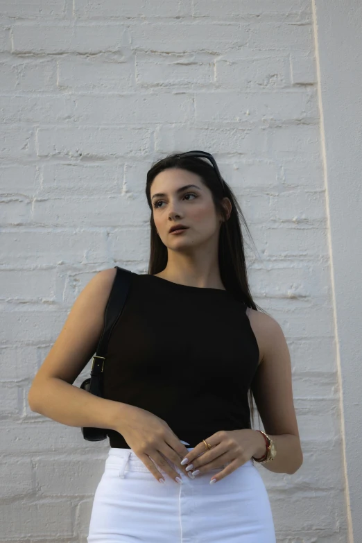 a young woman standing against a wall with her hands on her hip