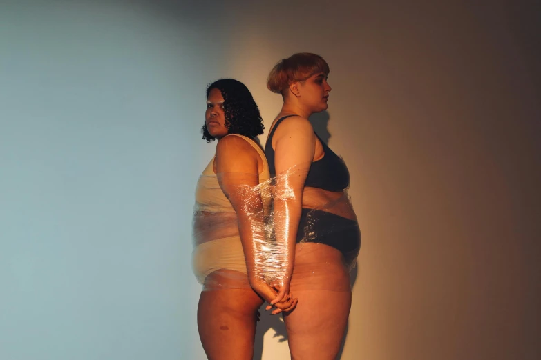 two women standing up together in shiny underwear