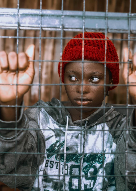 a  is making hand gestures behind a fence