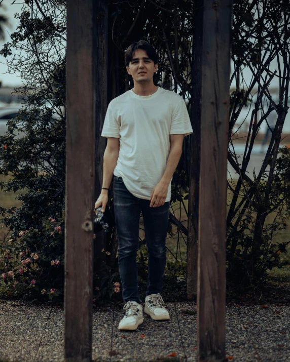 a man standing by a wooden arch with a camera