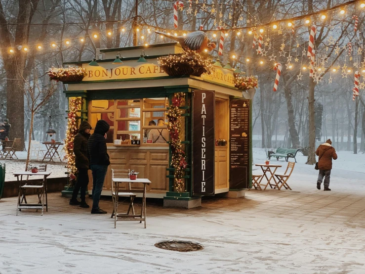 people stand outside in the snow while shops are decorated