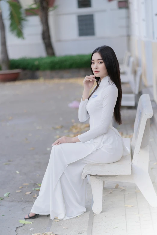 a woman is sitting on a bench in white