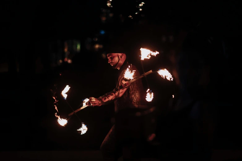 a man is dancing with fire stick in the dark