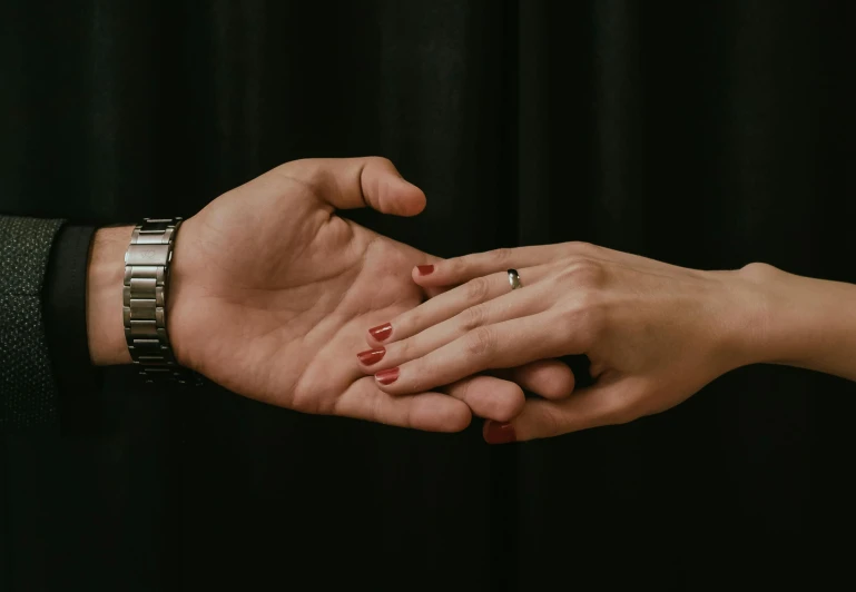 two hands holding each other while wearing different celets