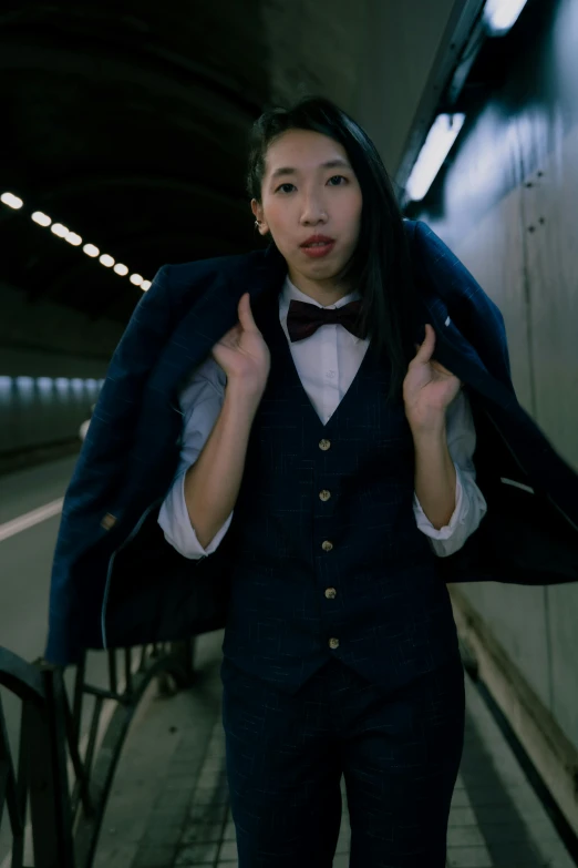 a woman in a blue suit and tie on a subway platform