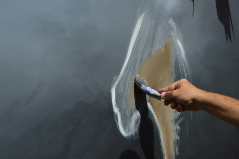 someone painting an object with white paint on black