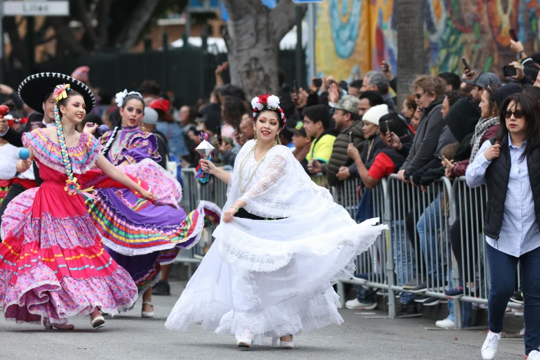 two people in costume and hats, walking around with a crowd of people behind them