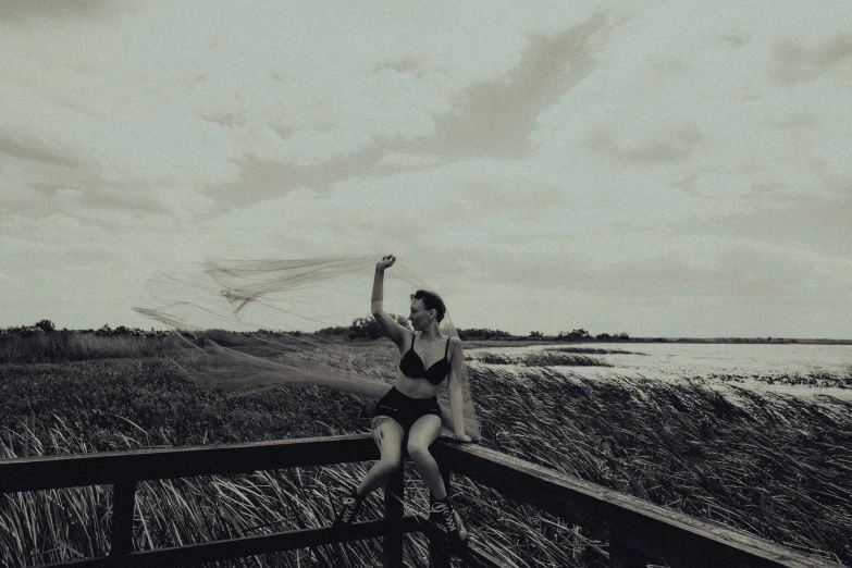 woman with arms raised holding up a frisbee in a landscape