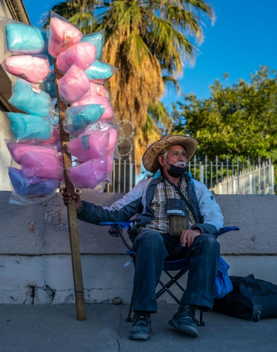 a man sitting on a chair next to a pole that is wrapped in colorful candy