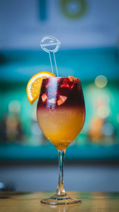 an orange slice is sticking out of the stem of a wineglass