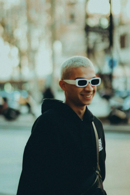 a man in a hoodie and sunglasses on the street