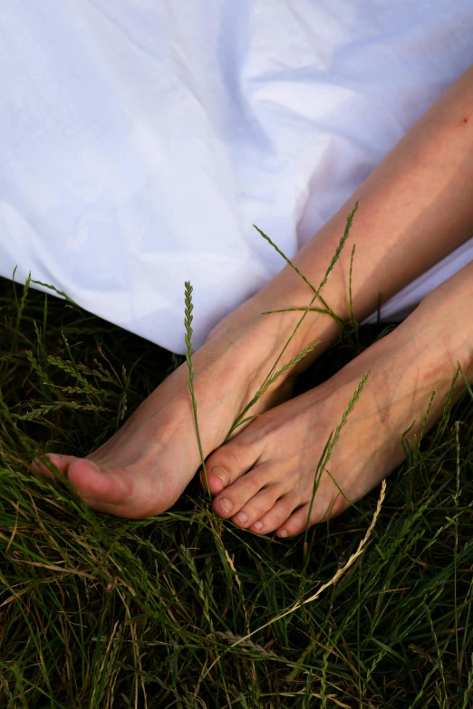 a person has grass on their feet by the blanket