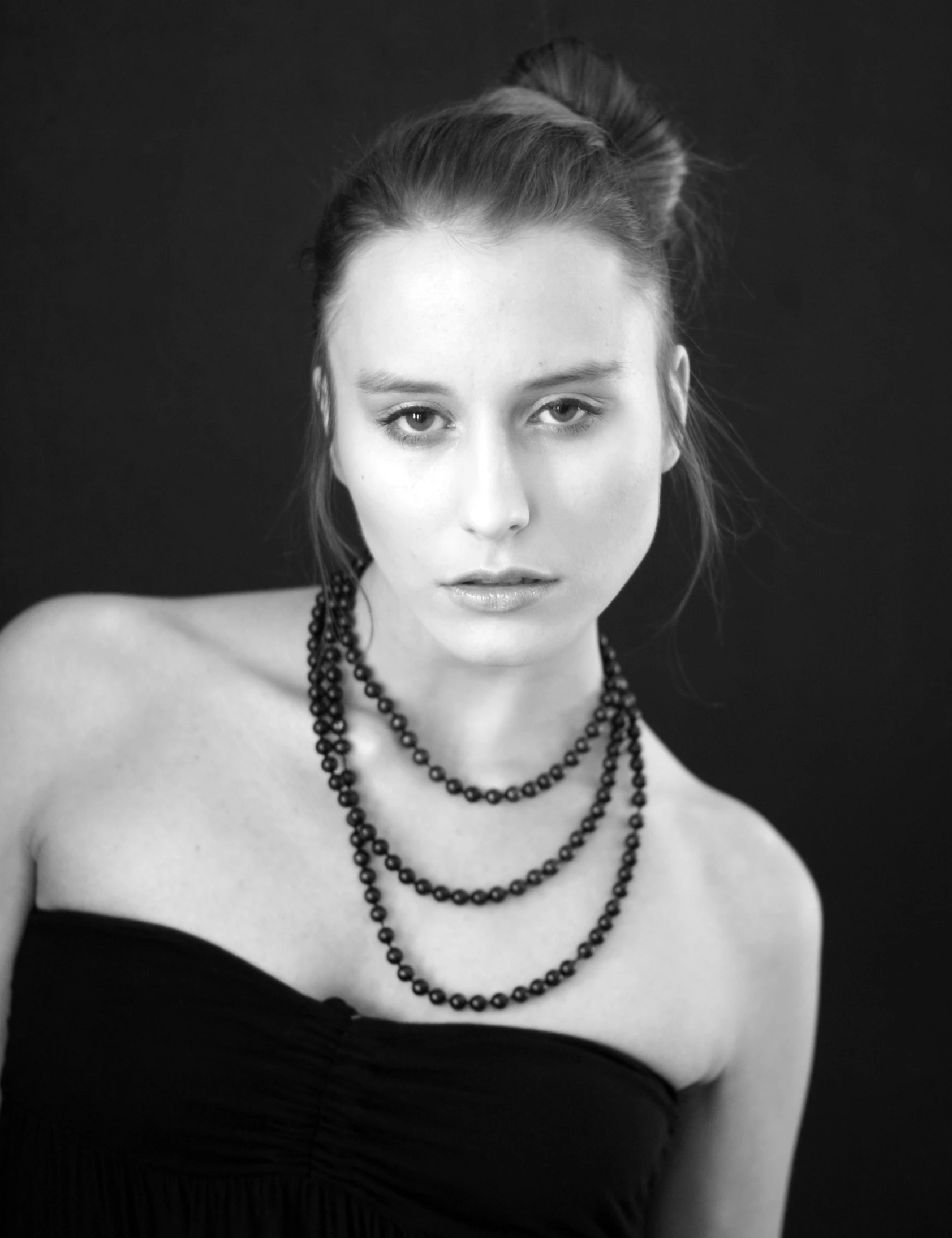 a woman poses for a studio portrait with a double necklace