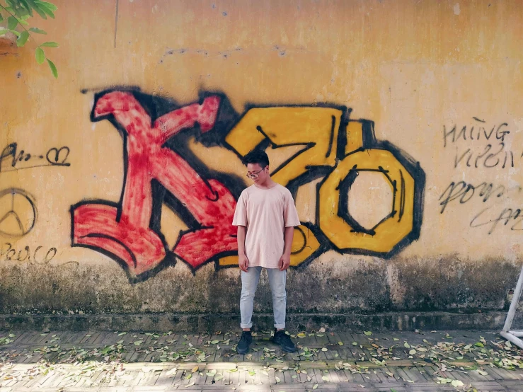 a man stands against graffiti on the side of an industrial building