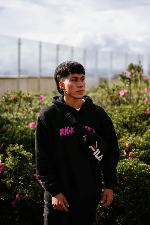 young man in black hoodie looking down outside