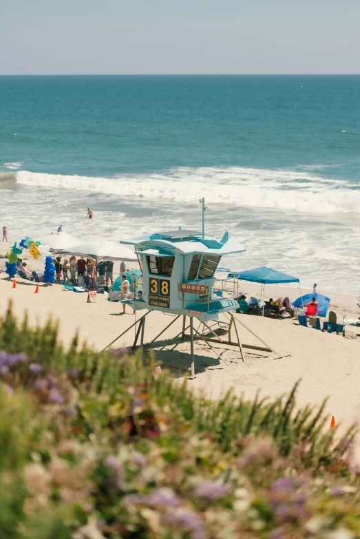 people stand on the beach where some umbrellas and chairs are