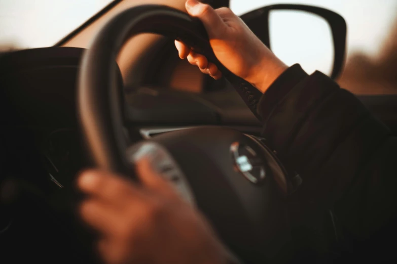 the driver of a car has their hand on the steering wheel