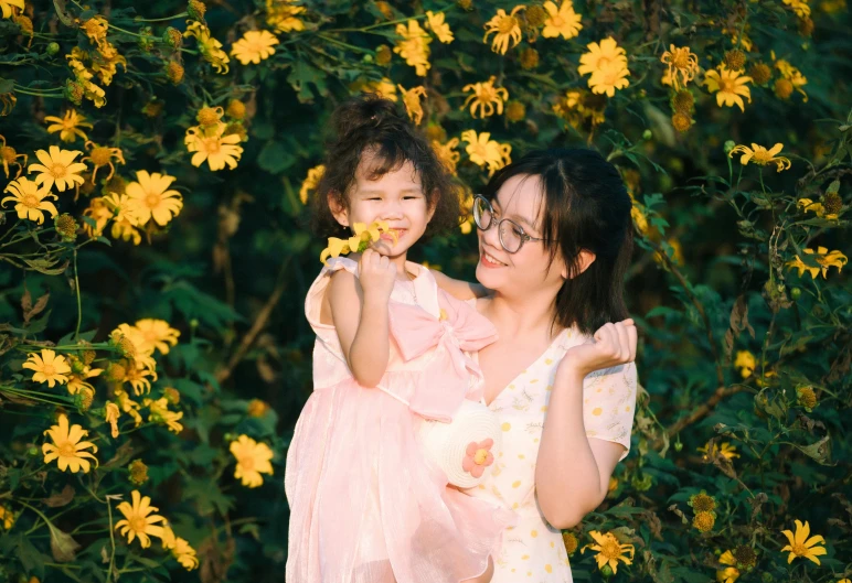 two women smile as they hold up young children