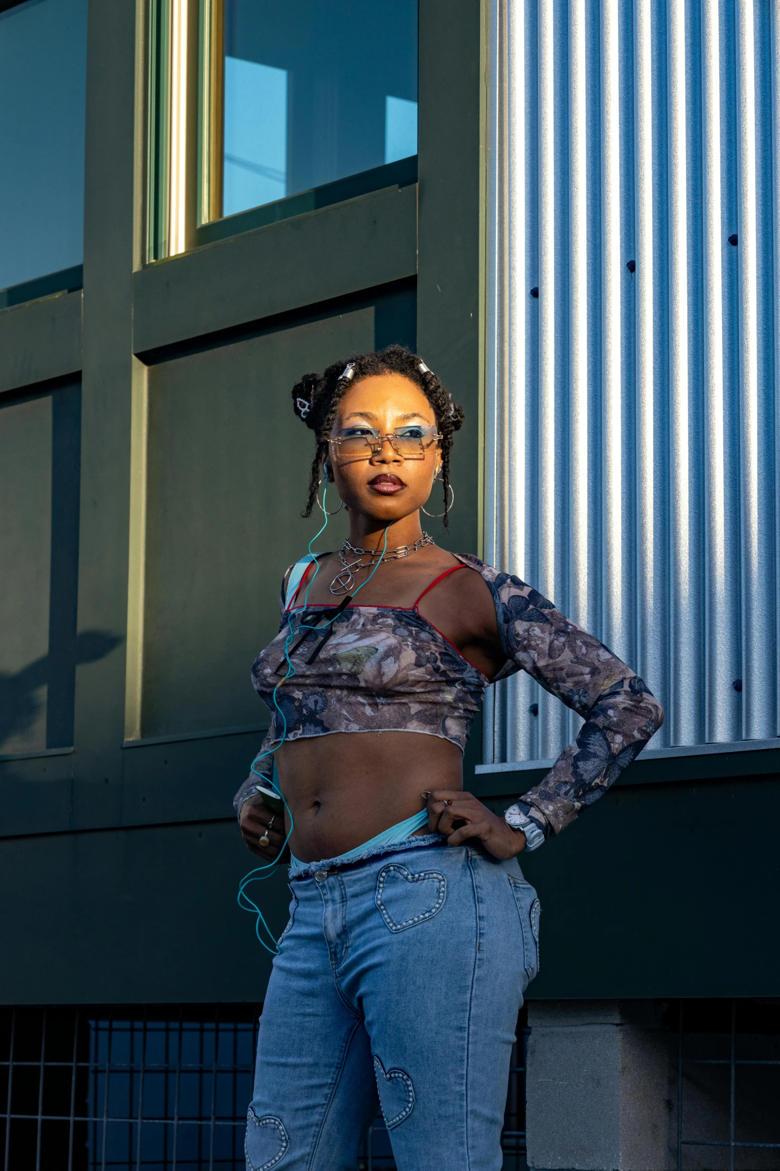 a young woman with sun glasses standing by a building