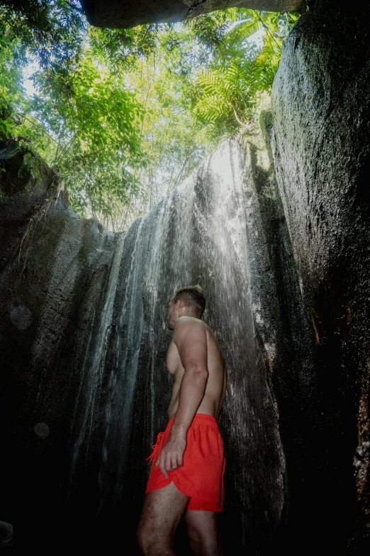 a guy in his underwear standing next to the waterfall