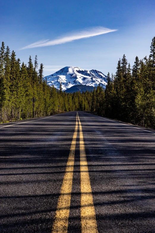 the road is lined with trees and mountains