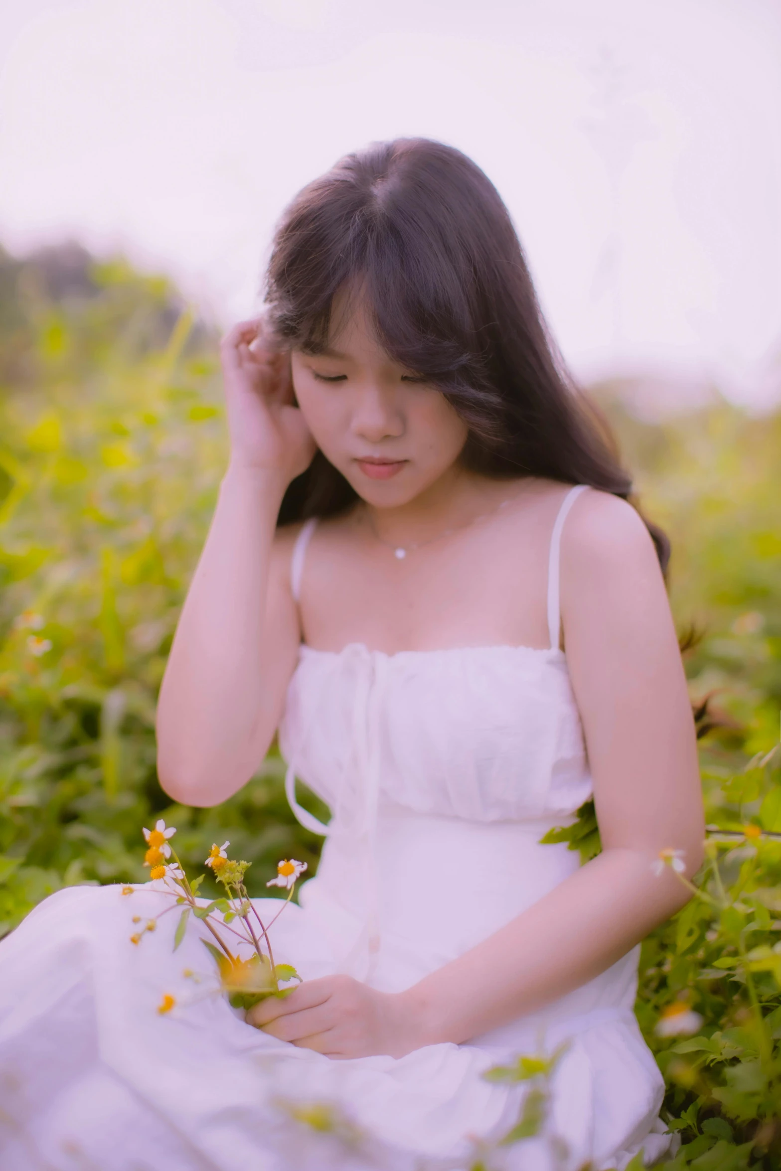 the woman is sitting in a field with flowers