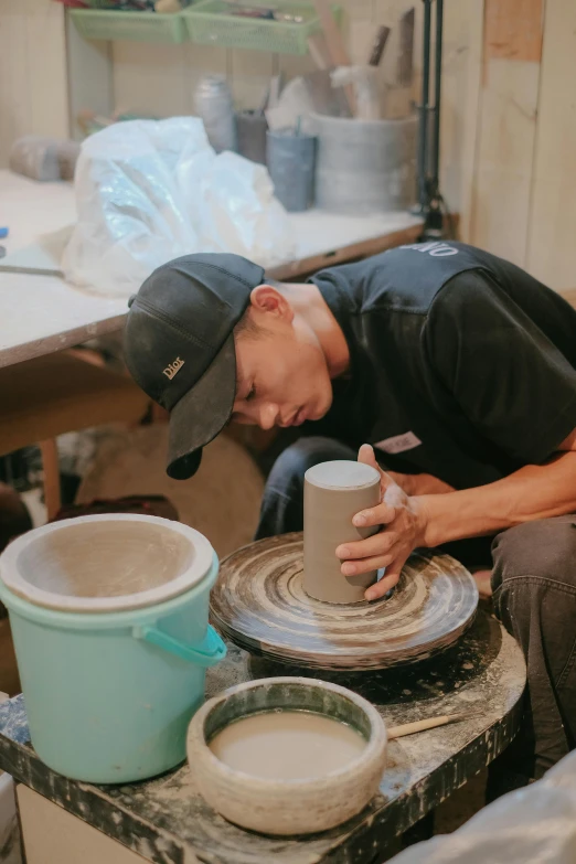 a man works with a pottery wheel and bucket