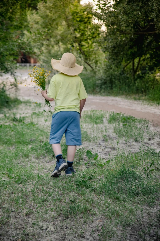 man with hat and yellow shirt carrying flowers walking