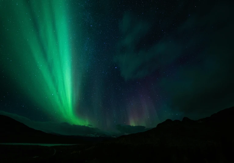 green and red lights over mountains under the night sky