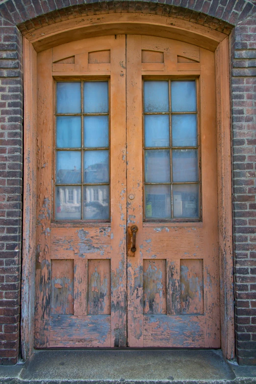 old wooden doors with glass windows on brick building