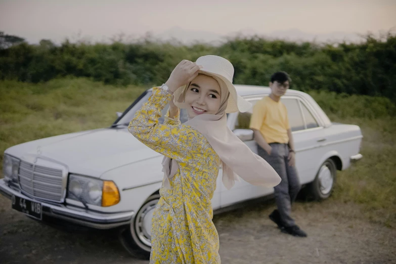 a person wearing a hat is posing next to a car