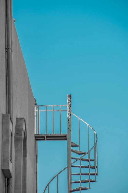 there is a tall spiral stair - railing against a blue sky