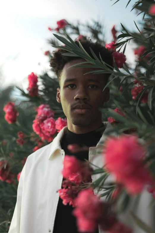 a young man is standing by some flowers