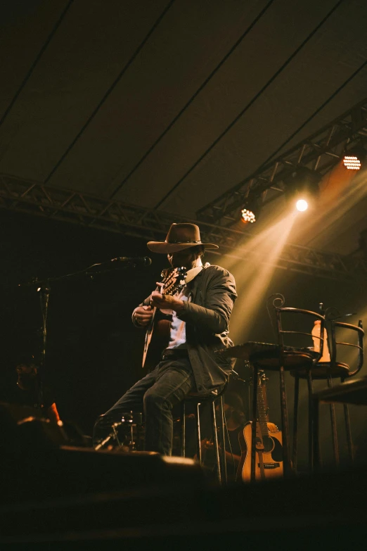 a man sitting at a stage with a guitar