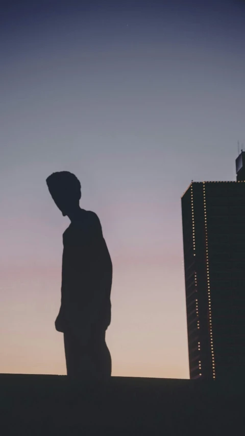 silhouette of a man on a roof with building in the background