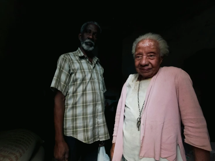 two men standing next to each other in a dark room