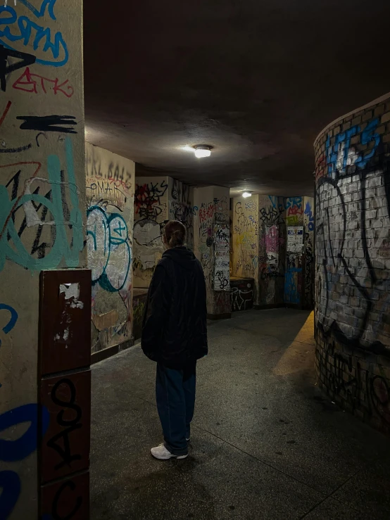 the man is standing in the alley near the wall