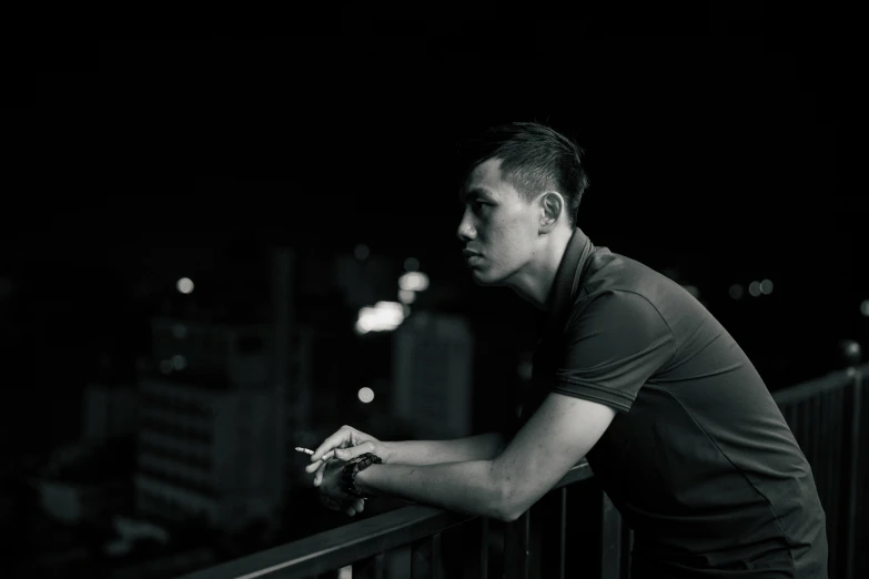 a man looking out over the edge of a balcony at night