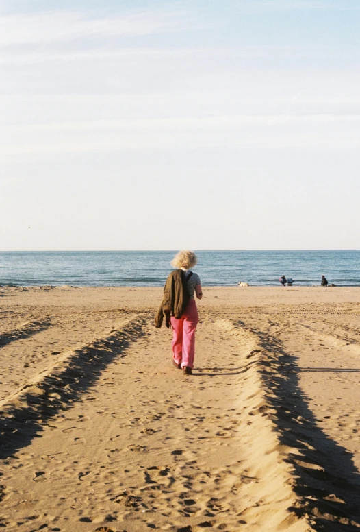 a person walking on a sandy beach with a water line behind them