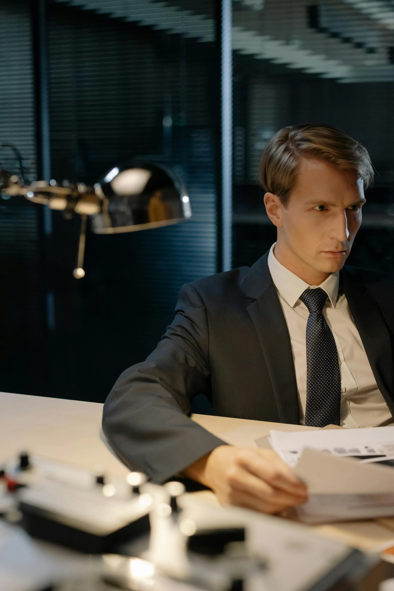 a man in business attire seated at a desk looking at paperwork