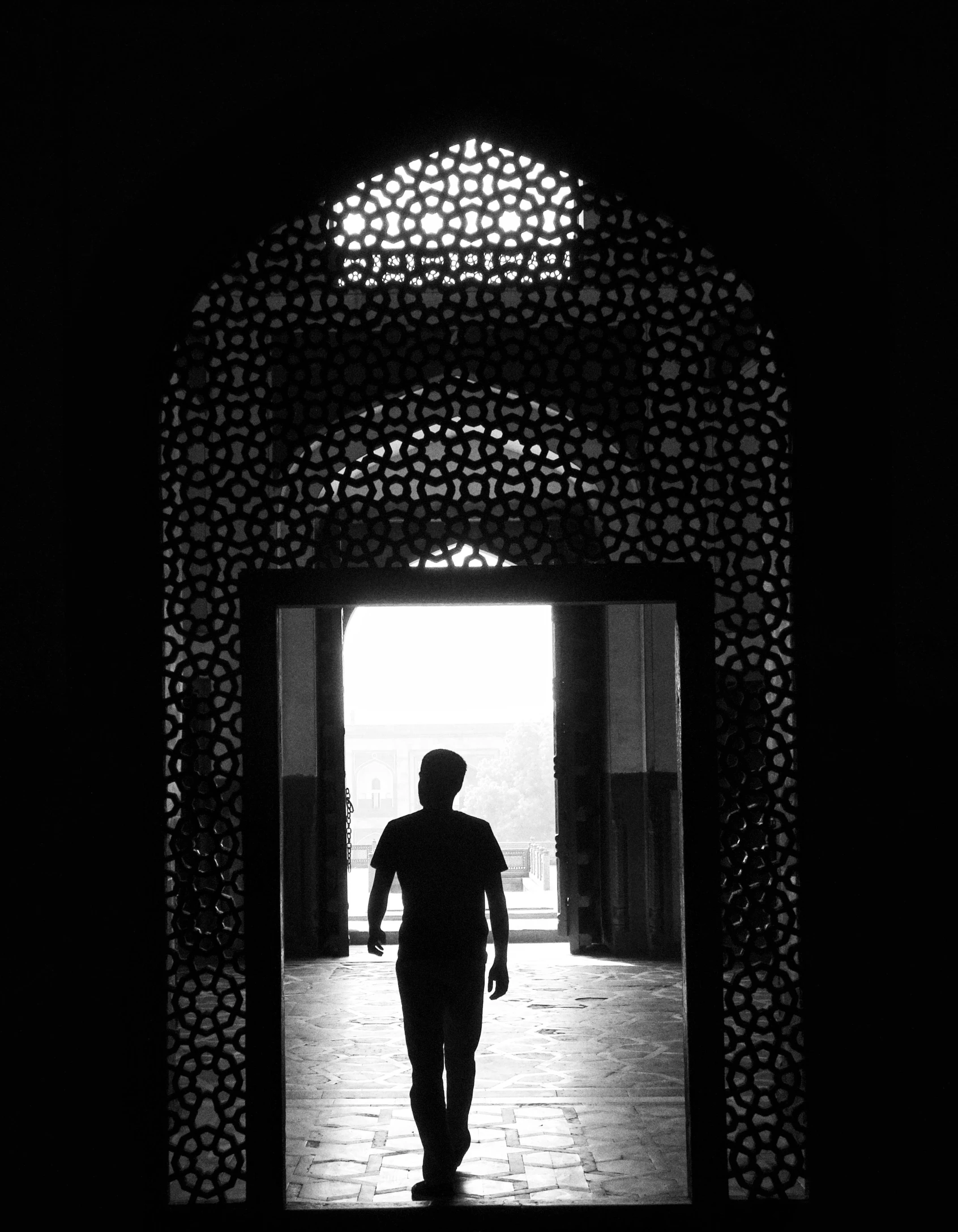 silhouetted man walks into a doorway in the shadow