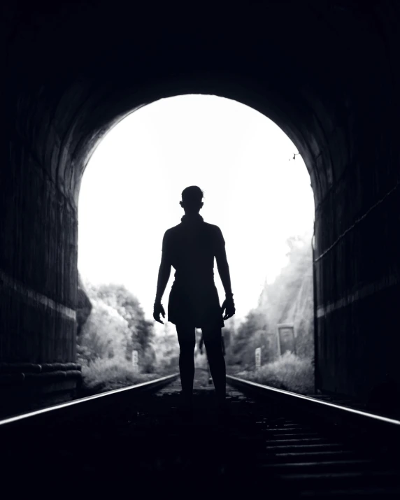 a person in a long coat is looking into a tunnel