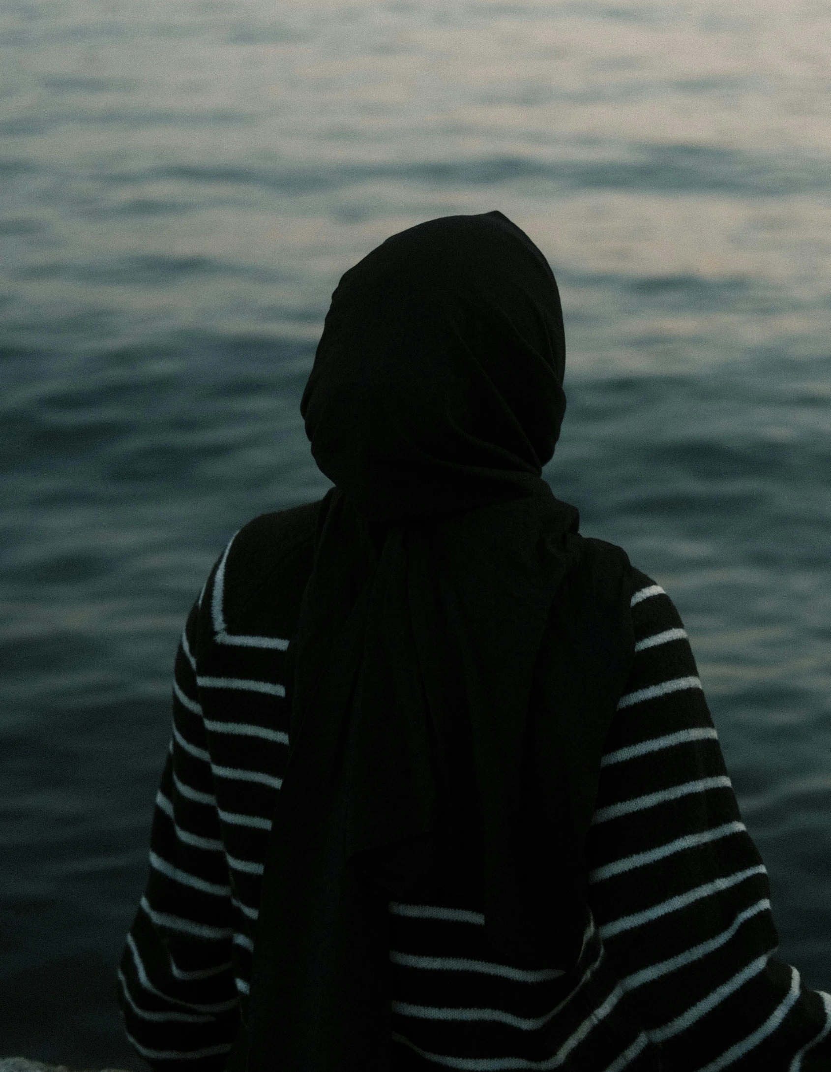 someone in striped shirt sitting by the water