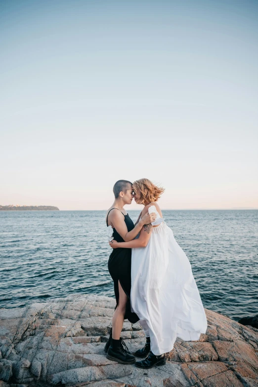 man and woman on rocks near water kissing